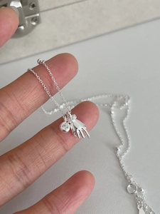 Macro shot of 925 sterling silver hand-shaped pendant with a sparkling zircon stone