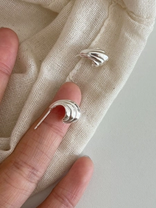 Gros plan de boucles d'oreilles géométriques en argent S925 avec motif ondulé texturé