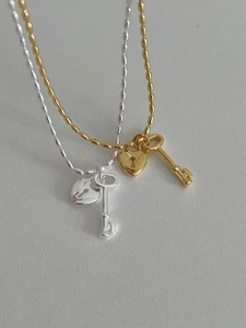 Macro detail of 925 sterling silver ball chain necklace with heart lock and key pendants