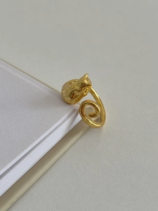 Detailed close-up of a golden cat-shaped 925 sterling silver ring on a notebook edge