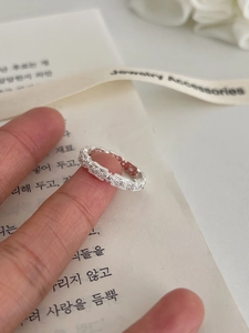 Close-up of a silver vintage lace ring with pavé diamonds on a hand with Korean books