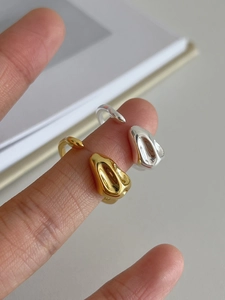 Macro shot of silver and gold irregular lava rings with liquid metal texture finish