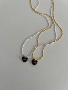 Detail of silver and gold rice grain chains with black heart pendants and Lucky text