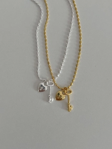 Detail view of heart lock and key pendants on beaded chains in silver and gold finishes