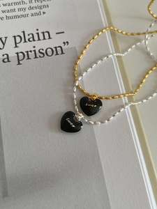 Macro detail of S925 silver and gold beaded necklaces with black enamel luck heart charms