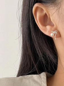 Gros plan de boucles d'oreilles nœud en argent 925 avec perles blanches sur l'oreille