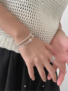 Close-up of minimalist S925 silver beaded bracelet and floral ring on a female model