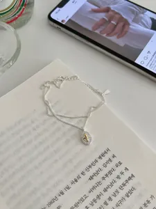 Detail view of a double-layered silver necklace with a sparkling iris crest pendant on a book