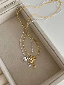 Detail of gold and silver heart key pendant necklaces on soft velvet jewelry box