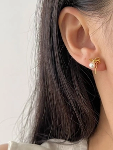 Gros plan d'une boucle d'oreille nœud en argent 925 avec perle sur l'oreille