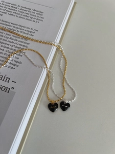Detail of silver and gold Lucky black enamel heart pendants on beaded olive chains