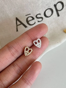 Detail of silver and gold heart stud earrings with cubic zirconia pavé setting