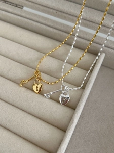 Macro shot of gold and silver heart lock and key pendant necklaces in a jewelry box