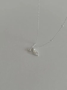 Detailed close-up of 925 sterling silver necklace featuring feather and zircon pendants