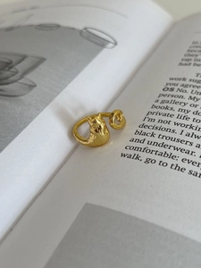Detail of a gold cat-shaped adjustable ring featuring embossed head and tail on an open band