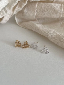 Detailed view of silver and gold heart stud earrings with sparkling cubic zirconia inlay