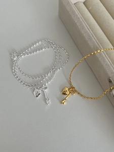 Detailed close-up of heart lock and key pendants on beaded bracelets in gold and silver