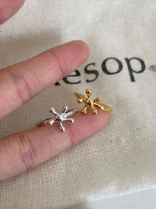 Close-up of adjustable silver and gold open rings with molten lava texture on a finger