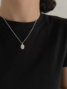 Detail of vintage oval pendant necklace with golden fleur-de-lis on silver base
