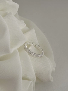 Macro shot of S925 silver hollow lace ring with pave set diamonds on white fabric