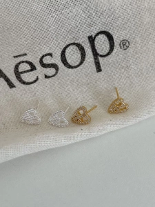 Close-up of gold and silver heart-shaped stud earrings set with white cubic zirconia