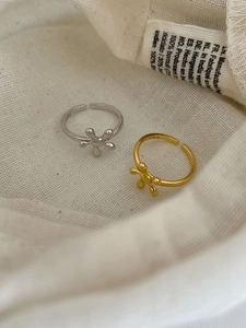 Close-up of gold and silver S925 sterling silver camellia rings on soft fabric