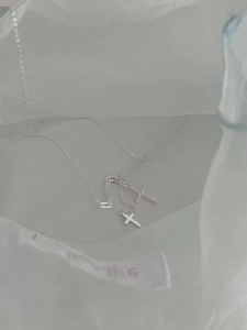 Dettaglio del ciondolo a doppia croce in argento con zirconi e catena sottile a O