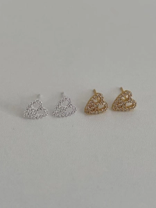 Close-up of heart-shaped silver and gold stud earrings set with sparkling zircon stones
