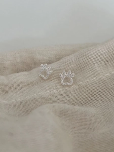 Macro detail of S925 silver hollow cat paw earrings with shimmering cubic zirconia