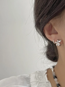 Close-up of a silver flower earring with five petals worn on a model's ear