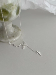 Dettaglio macro della collana a croce d'argento con cristalli su marmo