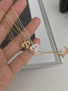 Macro shot of gold and silver fleur-de-lis pendants with sparkling cubic zirconia pavé