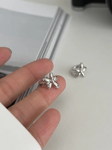 Macro detail of high-polish silver flower rings featuring a five-petal minimalist design