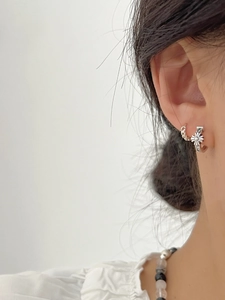 Close-up of S925 sterling silver hoop earrings set with twisted and daisy floral details
