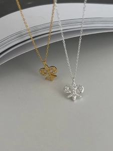 Macro shot of silver and gold Iris fleur-de-lis necklaces with sparkling zircon inlay