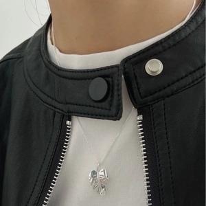 Collier minimaliste en argent 925 avec pendentif feuille de monstera sur veste en cuir noir