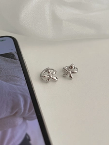 Detail view of silver floral hoop earrings with shiny petals on a white surface