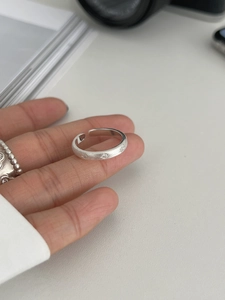Gros plan d'une bague en argent brossé mat avec gravures d'étoiles et anneau ouvert