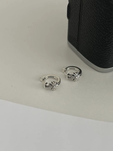 Close-up of vintage S925 sterling silver hoop earrings with embossed floral cross pattern