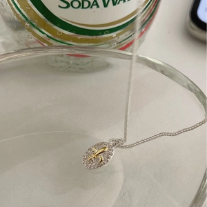 Elegant two-tone oval necklace featuring a golden Fleur-de-lis and zircon inlay