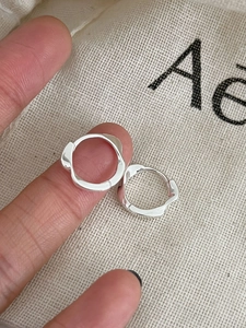 Détail macro de créoles Mobius en argent sterling 925 avec un design texturé ondulé chic