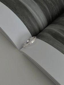 Détail d'une bague en argent brossé mat avec petits zircons étincelants sur papier