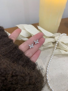 Detailed view of silver butterfly earrings with sparkling zircon stones held in hand