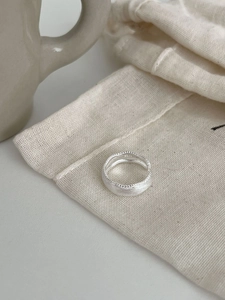 Dettaglio dell'anello in argento S925 con texture spazzolata e bordi perlati