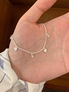 Detail of silver S925 drop necklace featuring heart pendants and sparkling zircon stones