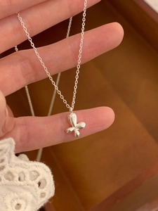 Close-up of a silver butterfly pendant necklace with polished mirror finish held by hand