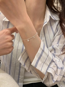 Detail of S925 sterling silver layered bracelet with heart charms and zirconia on a wrist