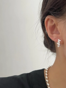Gros plan de boucles d'oreilles fleur en argent 925 mat et collier de perles sur modèle