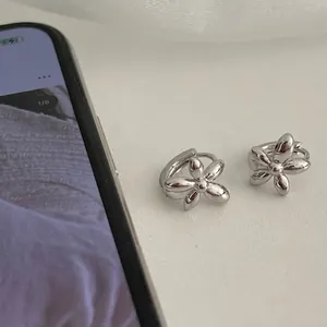 Minimalist silver flower hoop earrings with five-petal design on white background