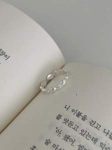 Macro detail of S925 silver geometric olive ring with zircons on a minimal book background
